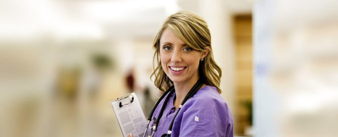 Female nurse smiling holding clipboard and stethoscope